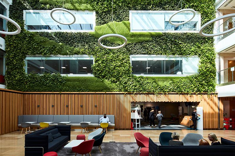 现代开放式办公接待空间，配有沙发和椅子，上层有绿色生活墙